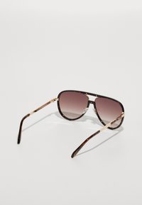 Gafas de sol marrón carey con lentes degradados. Acentos metálicos en las varillas; almohadillas nasales transparentes. Acabado brillante con variaciones sutiles en el patrón.