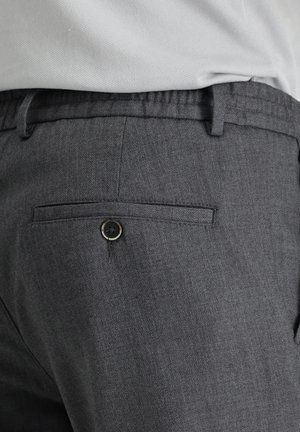 Pantalones gris oscuro hechos de una tela texturizada con una cinturilla elástica, que cuentan con un bolsillo trasero con un cierre de botón negro.