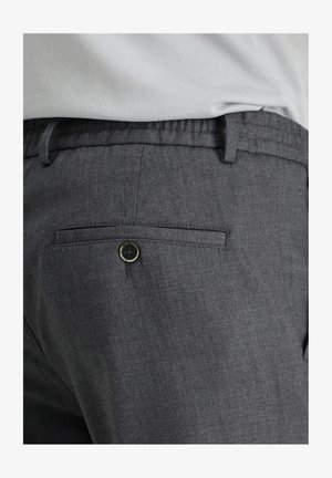 Donkergrijze broek gemaakt van een gestructureerde stof met een elastische tailleband, voorzien van een achterzak met een zwarte knoopsluiting.