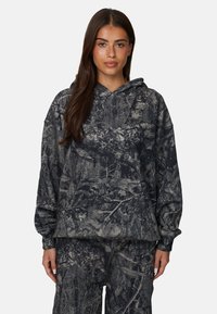 Hoodie w wzór kamuflażu w ciemnoszarym i czarnym kolorze, z przednią kieszenią i kapturem ze sznurkiem. Wykonany z miękkiego materiału o luźnym kroju.