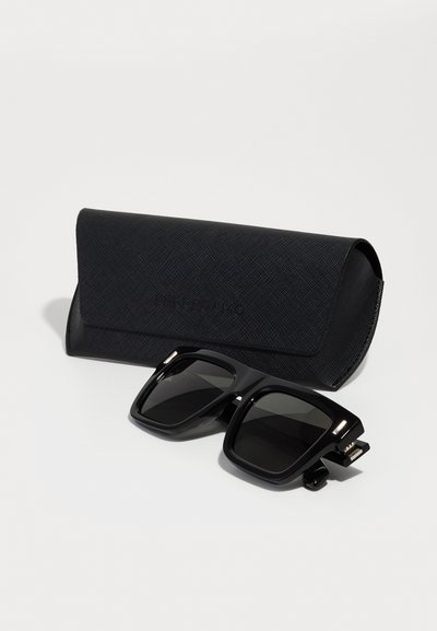 Black square sunglasses with tinted lenses, featuring a thick plastic frame. Accompanied by a black textured case with a magnetic closure.
