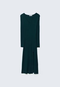 Robe en maille vert foncé à manches longues, avec un col en V et une fente à l'avant, suspendue sur un fond clair uni.