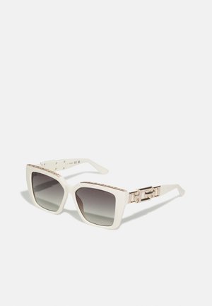Occhiali da sole bianchi oversize a forma quadrata con lenti scure sfumate, con un motivo a catena metallica dorata sulle astine e superfici testurizzate.