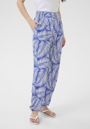 Le pantalon à motifs bleus et blancs présente des motifs feuillus, une taille élastique et des poches. Coupe décontractée avec des poignets fuselés, en tissu léger.