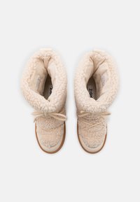 Beežid shearling-vooderdatud pahkluu saapad kummist tallaga, millel on tekstureeritud pealis, nöörkinnitusega disain ja pehme sisemus.