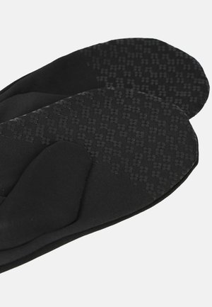 Black mittens with textured grip dots on the palm and fingers for enhanced hold and warmth.