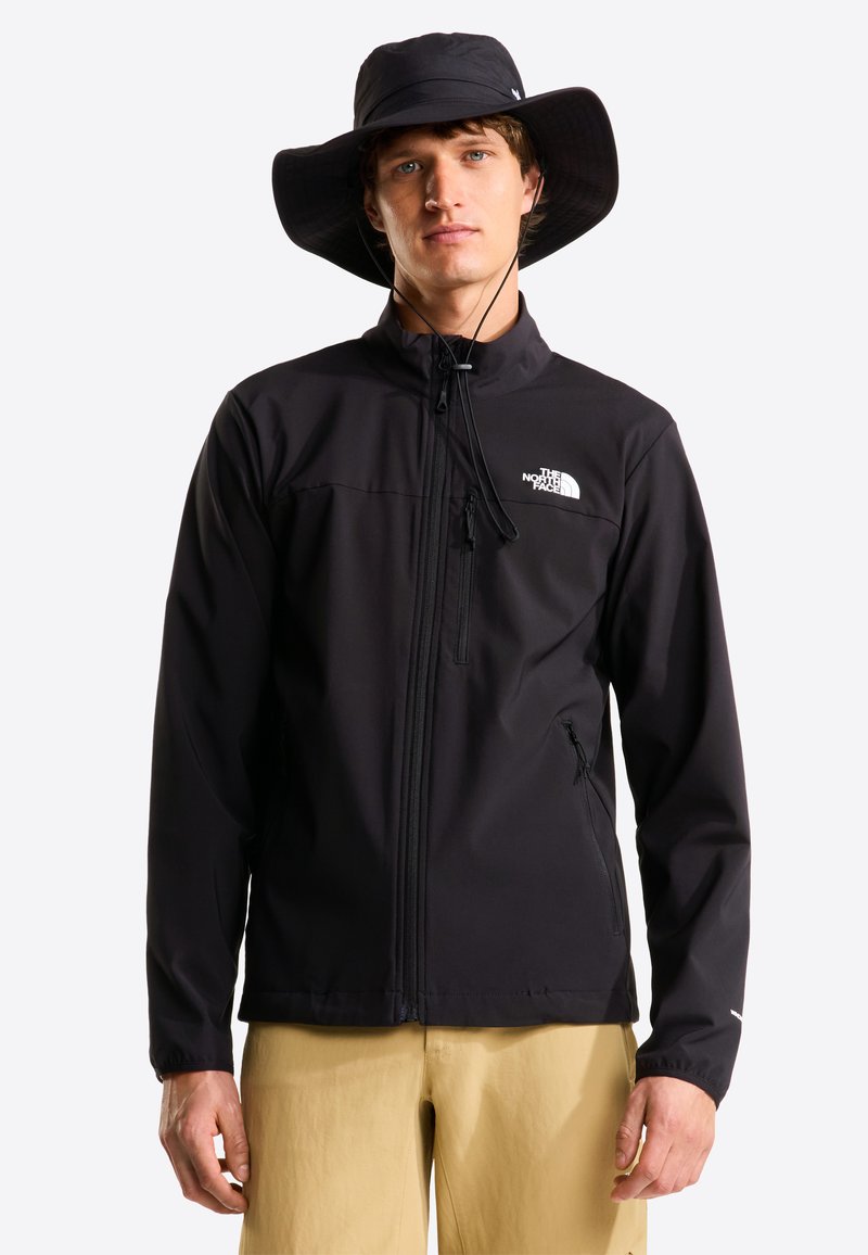 Μαύρο μπουφάν softshell με φερμουάρ, ψηλό γιακά και πλαϊνές τσέπες. Συνδυάζεται με μαύρο καπέλο με φαρδύ γείσο. Ομαλή υφή.