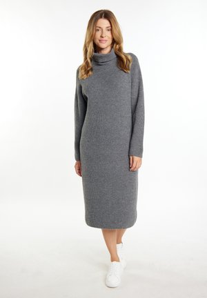 Graues geripptes Strickkleid mit hohem Kragen und langen Ärmeln, gerade geschnitten und knielang, kombiniert mit weißen Sneakers.