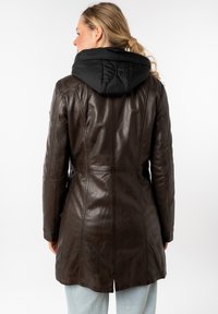 Manteau en cuir marron avec une capuche noire matelassée. Design ajusté, longueur mi-cuisse, surface texturée et détails de couture au dos.