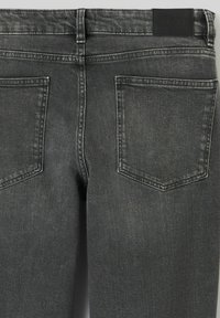Jean en denim gris foncé avec une taille haute, deux poches arrière et des variations de texture subtiles. Comprend une étiquette noire.