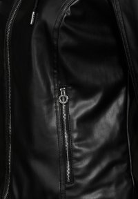 Giacca di pelle nera con tasca con zip in metallo argentato e texture liscia, che enfatizza il design elegante e i dettagli delle cuciture.