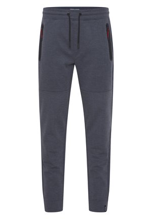 Pantalones jogger grises hechos de tejido texturizado, con una cinturilla elástica con cordones y bolsillos laterales con cremallera.