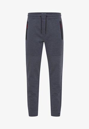 Grå joggebukser laget av teksturert stoff, med elastisk liv med snøring og glidelåslommer på sidene.