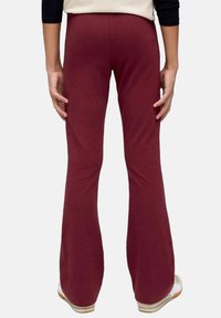 Bordeaux flared broek gemaakt van zachte stof met een gladde textuur, met een aansluitende taille en een uitlopende design bij de enkels.