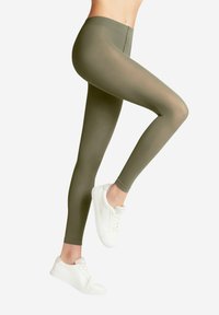 Olivgrüne Leggings aus dehnbarem Material mit glatter Textur, hoher Taille und figurbetontem Schnitt, kombiniert mit weißen Sneakers.