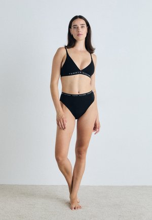 Černý bikiny set obsahující trojúhelníkovou podprsenku a vysoké kalhotky. Materiál je hladký; pás má logo "TOMMY HILFIGER" v kontrastních barvách.