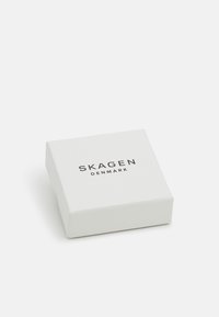Scatola regalo quadrata bianca con una superficie leggermente texturizzata. Presenta la scritta "SKAGEN DENMARK" stampata in nero sulla parte superiore. Design compatto.