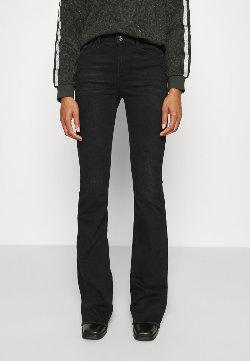 Jeans neri a campana realizzati in denim con una leggera lucentezza, caratterizzati da vita alta e design a cinque tasche. Accentuati da cuciture sottili.