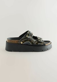 Sandalias de plataforma negras con adornos de cuentas, hebillas ajustables y una plantilla de corcho texturizada; suela de goma con ranuras para mayor tracción.