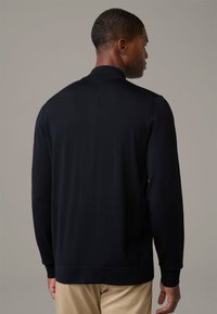 Dunkelblauer Strickpullover mit hohem Kragen, gerippten Bündchen und Saum. Weiche Textur und taillierte Form. Ansicht von hinten, die eine glatte Verarbeitung zeigt.
