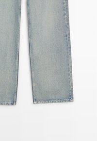 Jean en denim bleu clair avec jambes droites, présenté de la mi-cuisse jusqu'à l'ourlet sur fond blanc.