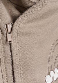 Beige Zip-Hoodie mit glattem Stoff, gerippten Kanten und einem gestickten Design von einer Wolke mit Regenbogen auf der Vorderseite.