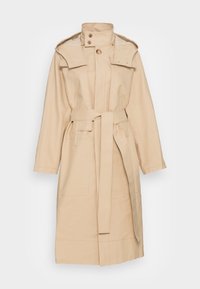 Trench-coat long beige avec un col montant, une capuche amovible, des boutons à l’avant et une ceinture en tissu à la taille.