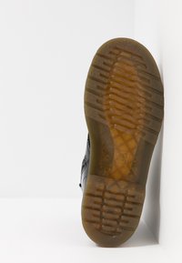 Schwarzer Sneaker mit einer strukturierten Lederoberschicht und einer Sohle aus Gummilaufsohle. Die Sohle verfügt über ein Muster für Traktion, das Grip und Haltbarkeit verbessert.