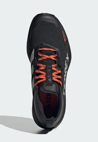 Chaussures de sport noires avec une tige en maille respirante, des lacets orange et une semelle extérieure en caoutchouc. Les caractéristiques incluent un col rembourré et la marque Gore-Tex.