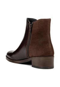 Stivale alla caviglia marrone con parte anteriore in pelle liscia, retro in suede, cerniera laterale e tacco basso impilato su sfondo bianco.