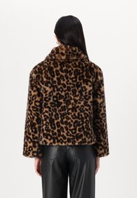 Veste en fausse fourrure au motif léopard, avec un large col et une coupe courte. Les manches sont droites et arrivent au poignet.