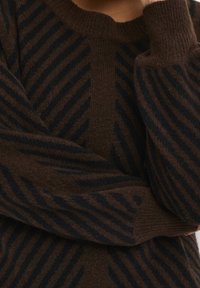 Brauner Pullover mit horizontalen und diagonalen dunkelblauen Streifen, gefertigt aus weichem, strukturiertem Strick mit gerippten Bündchen und Halsausschnitt.