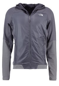 Herrgrå zipjacka med texturerad huva, kontrasterande ärmar, meshdetaljer och sidofickor med dragkedja. Tillverkad av lätt och ventilerande tyg.