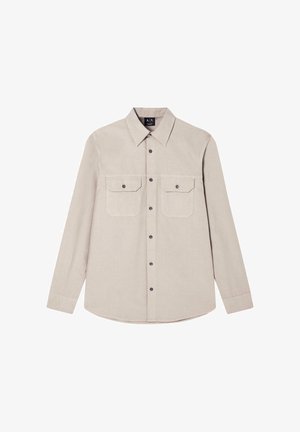 Chemise beige à manches longues avec deux poches devant, col pointu et boutons noirs au centre et sur les poches.