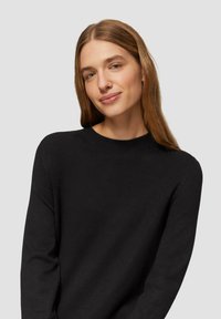 Schwarzer Strickpullover mit Rundhalsausschnitt, langen Ärmeln und glatter Textur. Schlichte, klassische Silhouette.