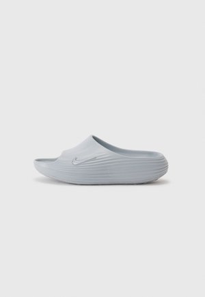 Jasnoszary sandał typu slide marki Nike z teksturowanymi rowkami i uniesionym logo Nike po boku, pokazany z boku.