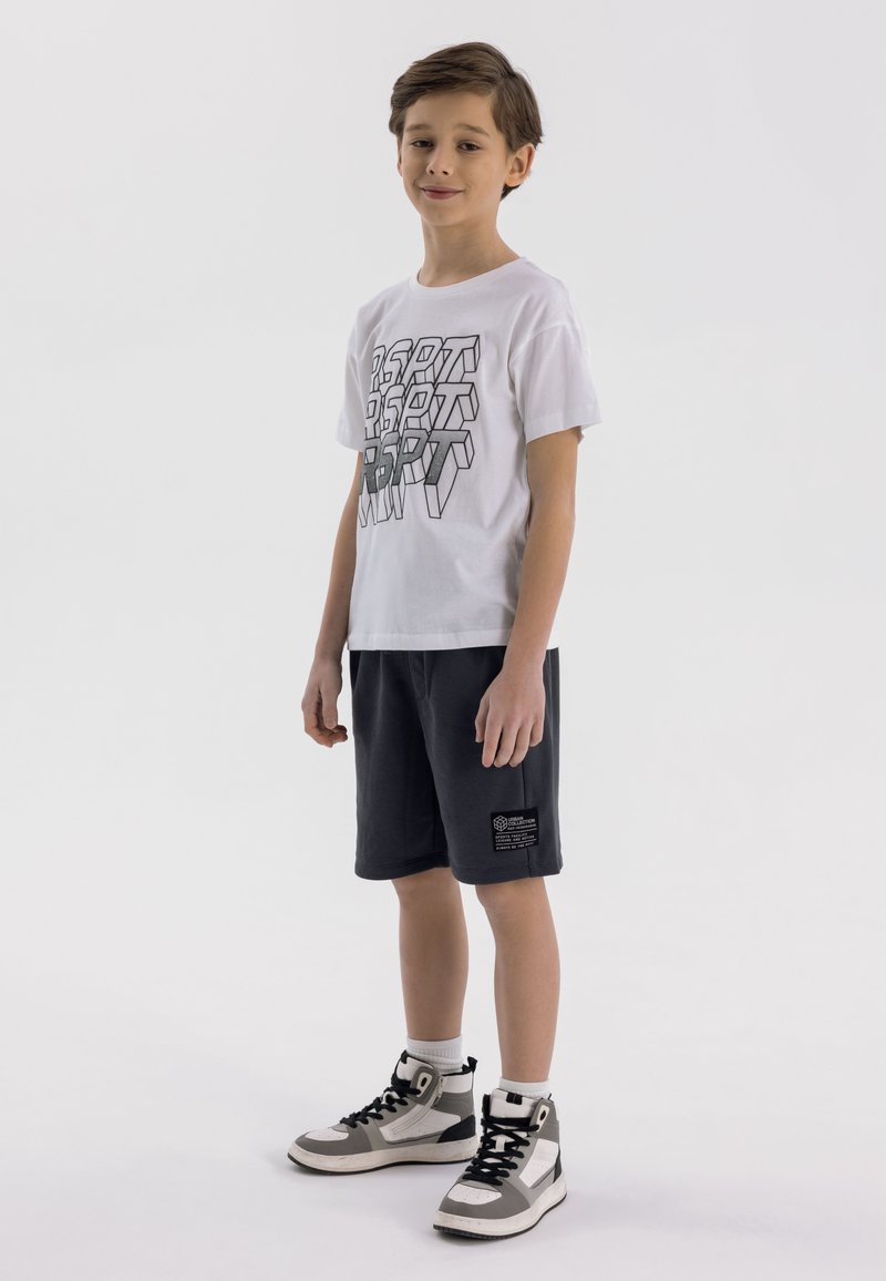 White short-sleeve T-shirt with black graphic text, paired with navy shorts and gray high-top sneakers featuring black and white accents.
