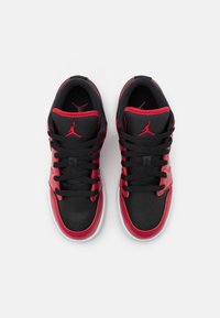 Baskets noires et rouges avec une tige en cuir et textile, présentant une texture lisse, un bout rond, des lacets plats et des accents de logo emblématiques.