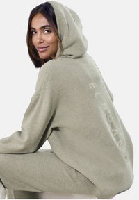 Hellgrüner Kapuzenpullover aus weichem Stoff, mit einem lockeren Schnitt und gerippten Bündchen. "ELBSAND"-Logo dezent auf der Rückseite gedruckt.