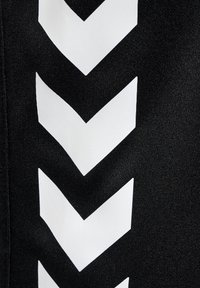 Svart tyg med iögonfallande vita chevronmönster, med en slät textur och rena linjer, som huvudsakligen täcker ena sidan.