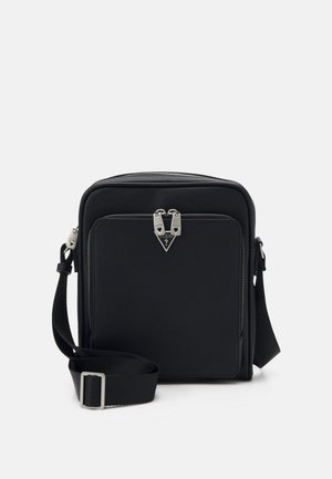 Sac bandoulière synthétique noir de forme rectangulaire, fermeture éclair, accents en métal argenté et bandoulière réglable.