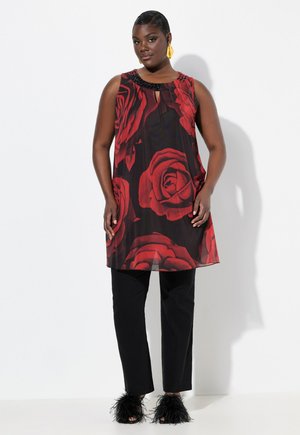 Abito nero con grande stampa di rose rosse, senza maniche, con scollatura a chiave e dettagli con perline. Abbinato a pantaloni neri e sandali con bordo in pelliccia.