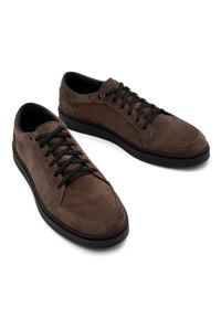 Baskets en suede marron avec lacets noirs, bout rond et semelle en caoutchouc. Présente des détails de couture et un design minimaliste.