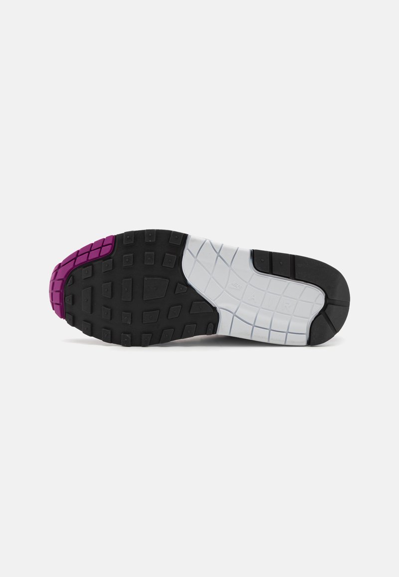 Schoenzool met een zwart, wit en paars rubberen profiel, voorzien van vierkante en rechthoekige gripstructuren en de tekst "NIKE AIR" in reliëf op het witte gedeelte.