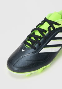 Zwarte en neon groene voetbalschoenen met een gestructureerd leren bovenwerk, zwarte veters, witte strepen en een rubberen buitenzool met studs.