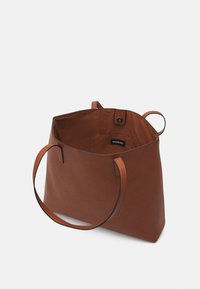 Borsa tote in finta pelle marrone con manici doppi, una forma flessibile e chiusura magnetica. L'interno presenta una tasca brandizzata. Texture liscia.