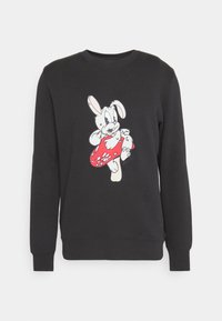 Sudadera negra con un gráfico de un conejo de dibujos animados en blanco y rojo, con un objeto redondo rojo y detalles distintivos en las orejas y ojos.