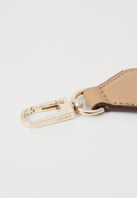 Portachiavi in pelle marrone con accessori in metallo color oro. Presenta un gancio e un anello per il fissaggio. Textura liscia con dettagli di cucitura visibili.