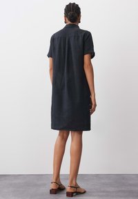 Schwarzes Leinenhemdkleid mit kurzen Ärmeln, Knopfkragen und legerem Schnitt, mit gerader Silhouette und knie-langer Länge.