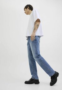 Camiseta de algodón blanca, jeans de mezclilla azul claro y zapatos negros con cordones. Corte recto con un diseño casual. Estilo minimalista, sin patrones.